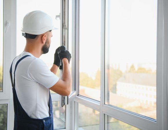 Construction worker installing window in house. Handyman fixing the window with screwdriver.